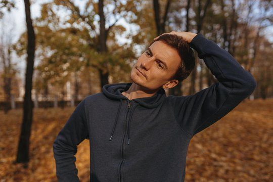 male athlete stretching neck and doing warm up while exercising during fitness training in park