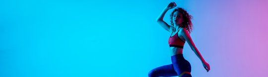 young beautiful woman in bright sportwear isolated on gradient pink blue background in neon light