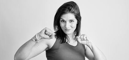 sportliche frau pilatestrainerin haelt faeuste hoch fitnessmotivation