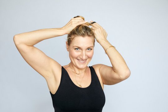 sportliche blonde frau bindet sich die haare vor dem pilates workout